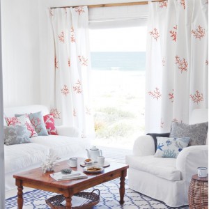 Coral patterned white curtains with white sofas and blue patterned rug